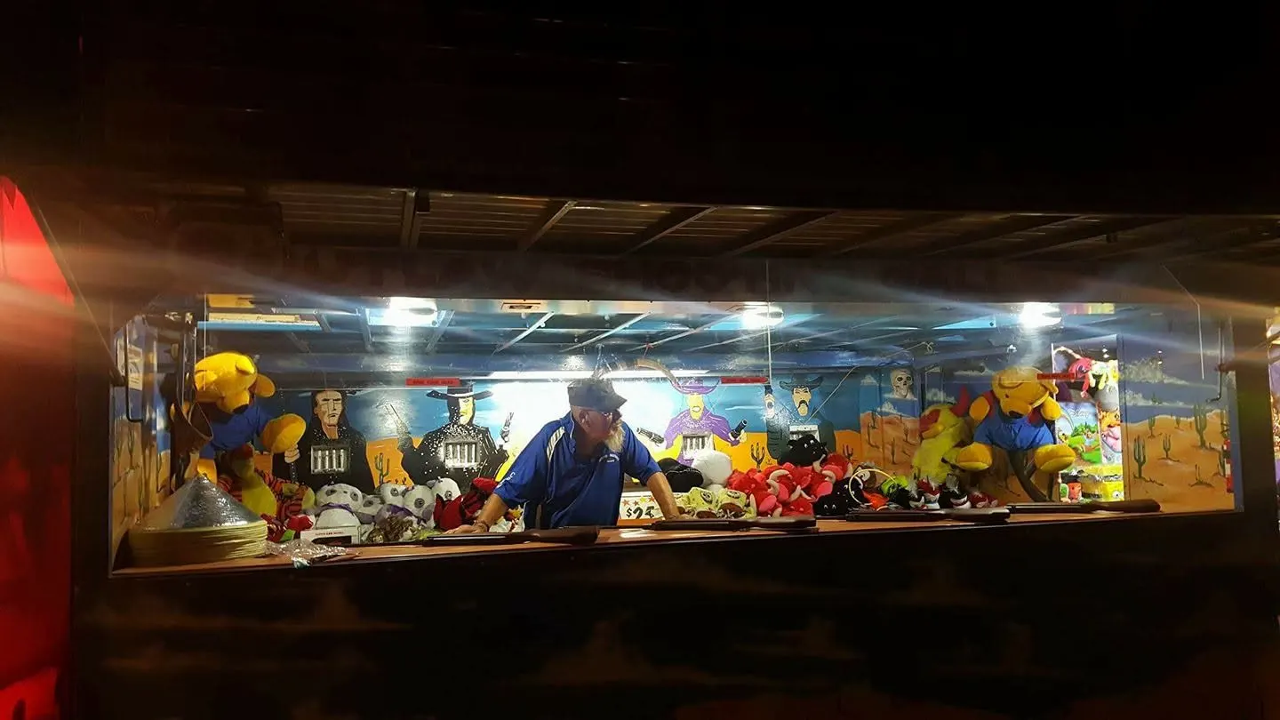 Game stall lit up at night with prizes on display