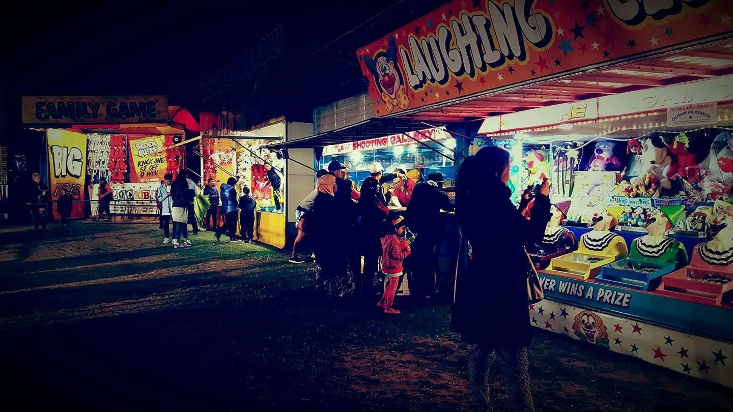 Crowd gathered around lit-up game stalls at night
