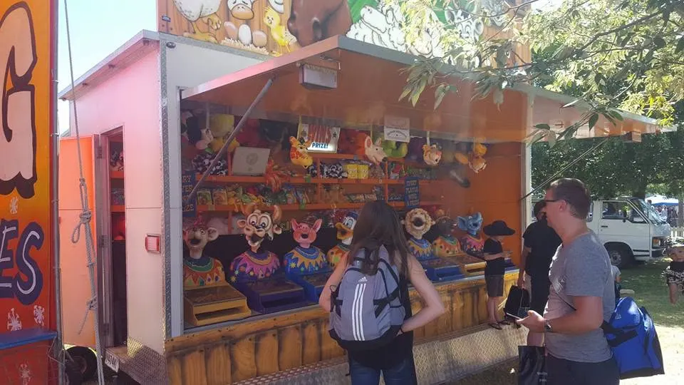 Daytime game stall with plush prizes and painted clown figures