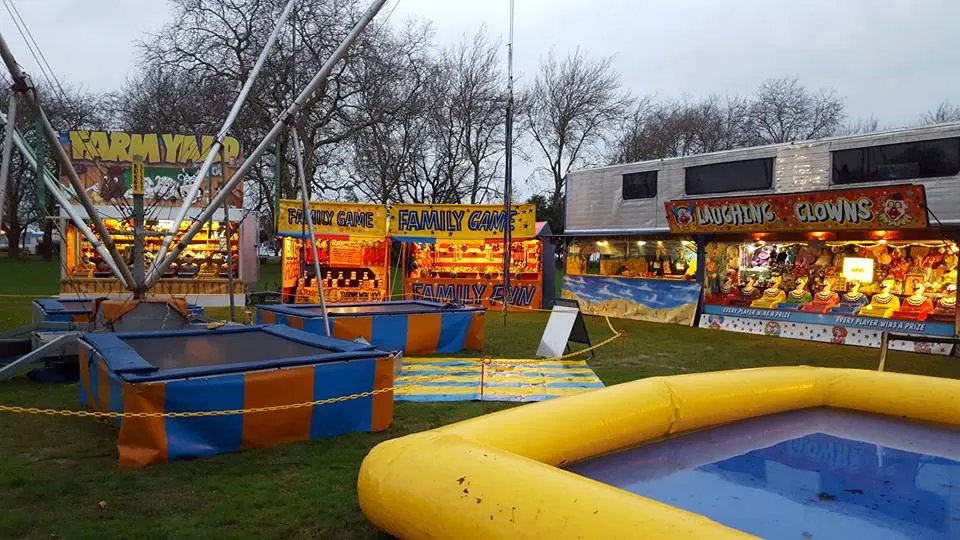 Bungy trampolines and game stalls spread across a lawn
