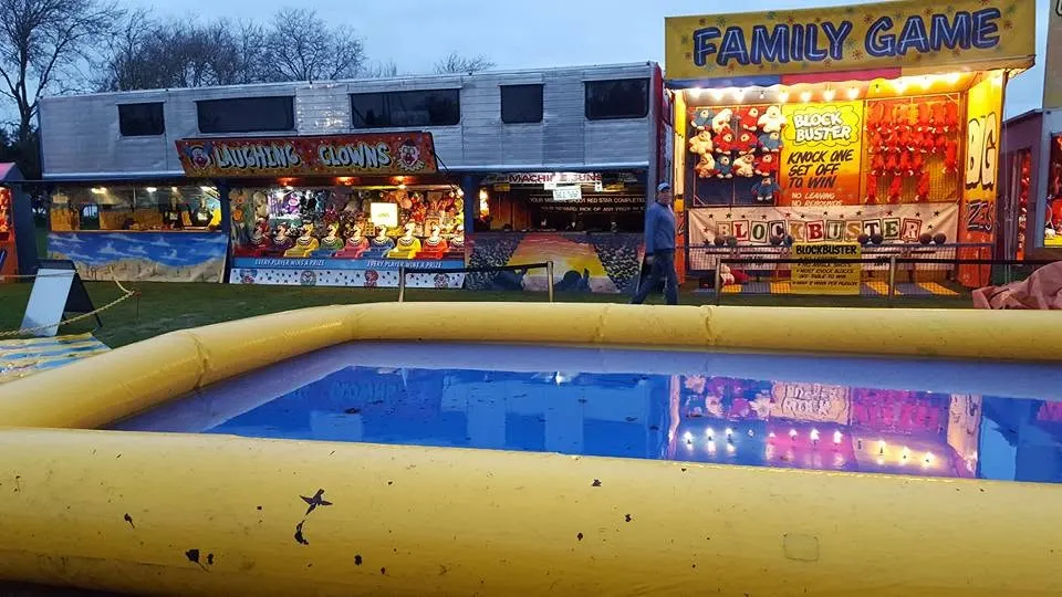 Inflatable pool in front of game stalls lit up at dusk