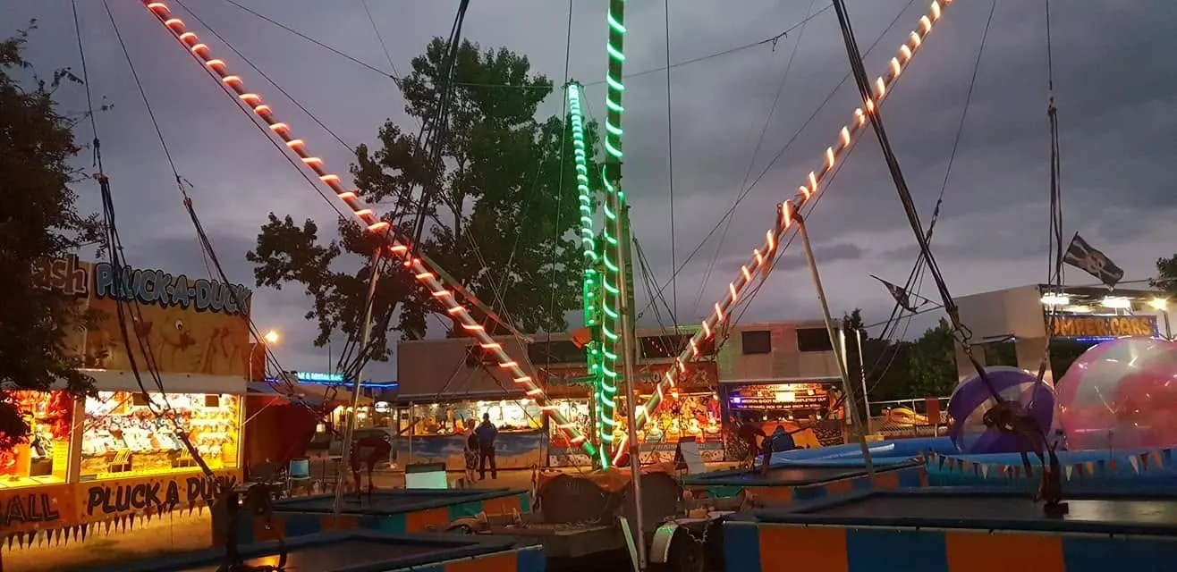 Strings of coloured lights over bungy trampolines at dusk