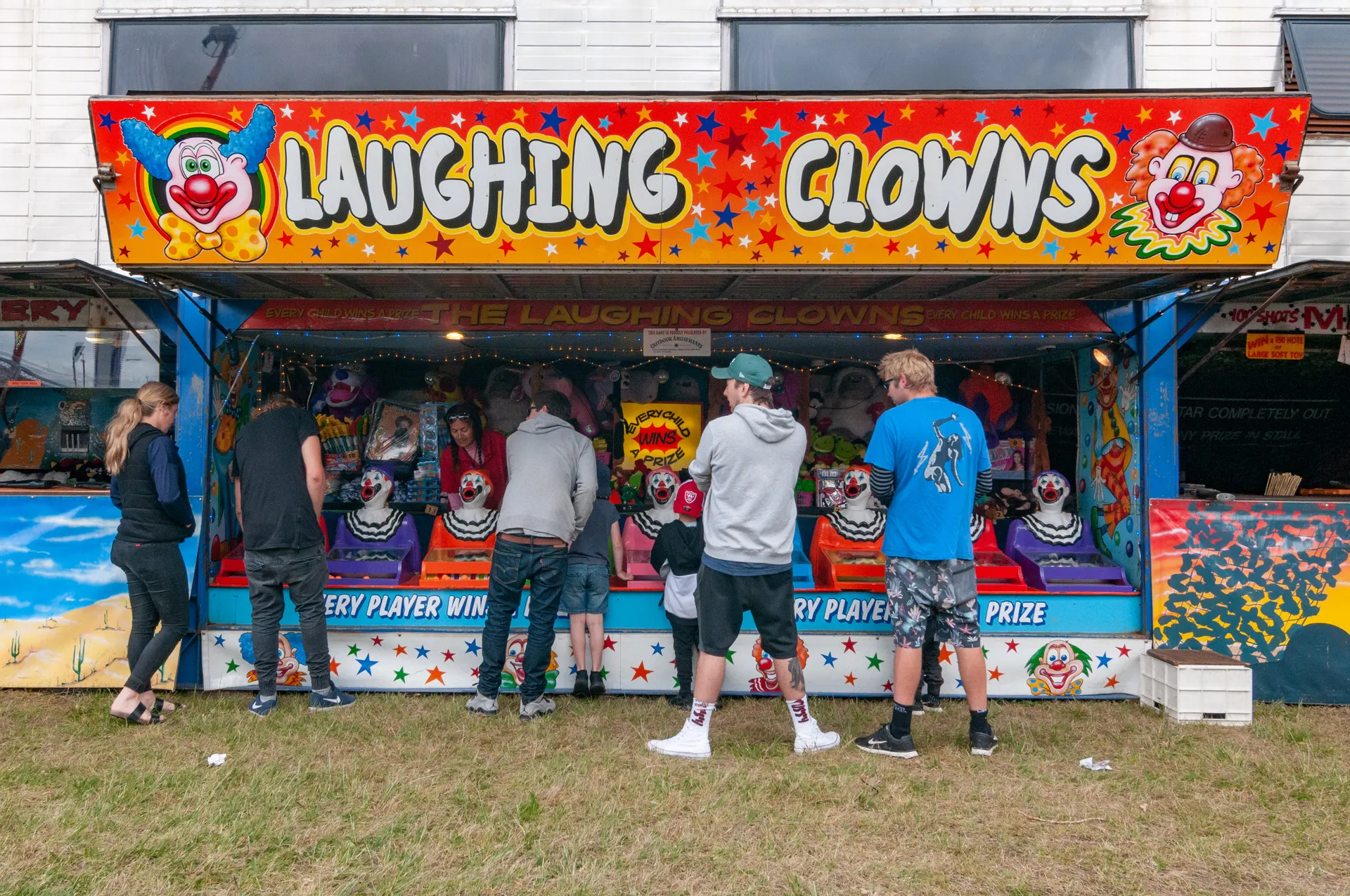 Clown-themed game booth with visitors gathered in front