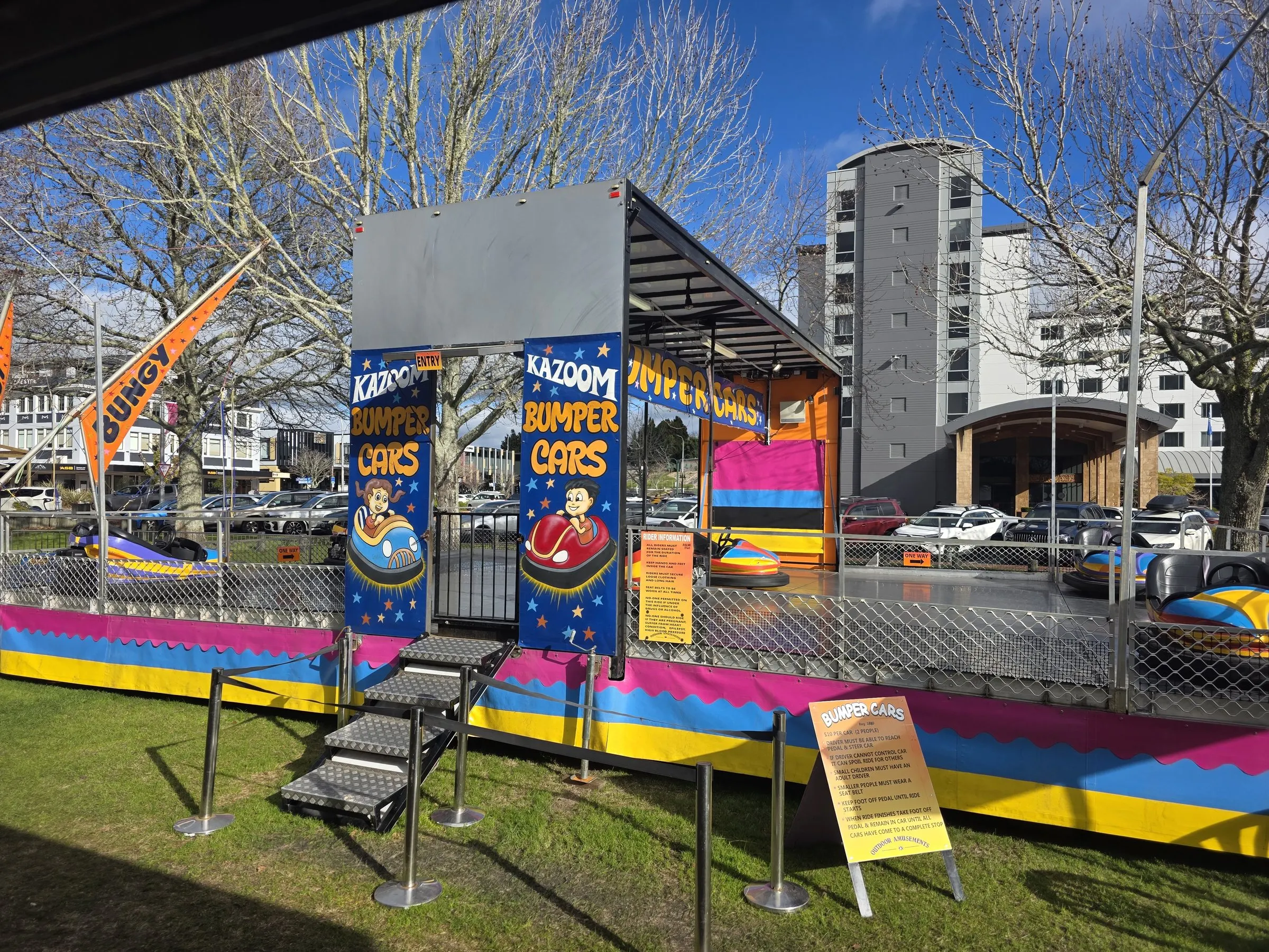 Bumper car arena with Kazoom Bumper Cars banners and a striped ramp on a sunny day