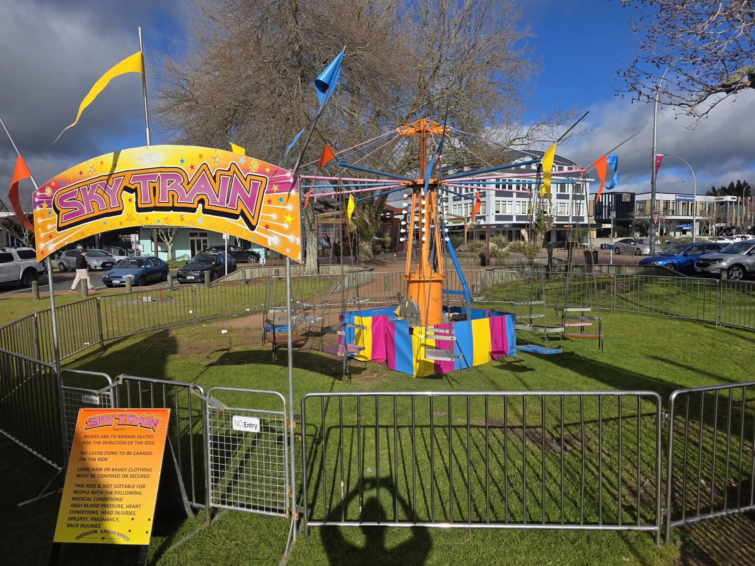 Sky Train swing ride under a colourful arch with pennant flags