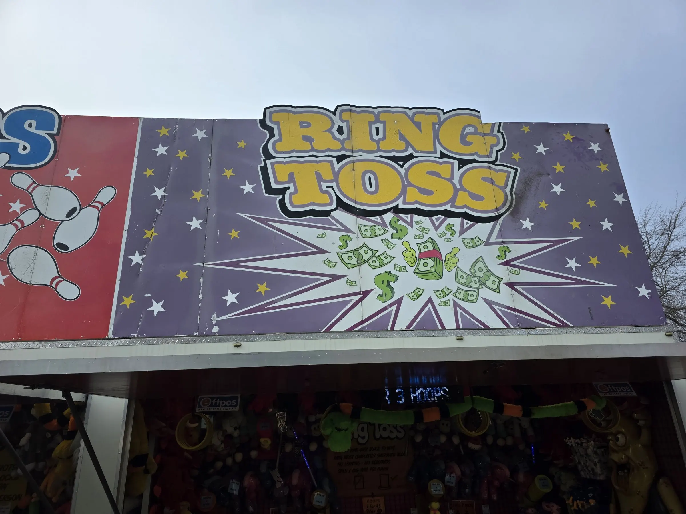 Ring Toss stall with a purple starry sign against a cloudy sky